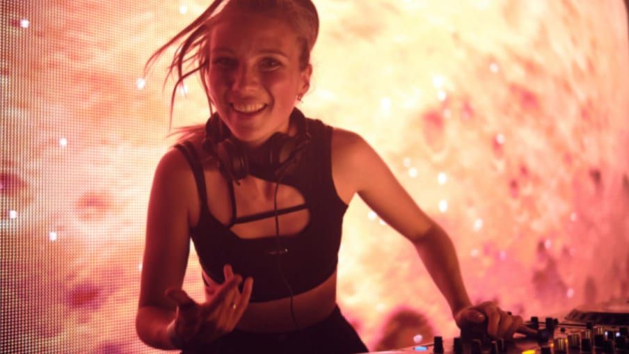 Angie Mill, die Gewinnerin des CUPRA Young Talents DJ Contests von 2023, posiert selbstbewusst und strahlt vor einem minimalistischen Hintergrund.